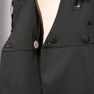 Detailaufnahme eines eleganten schwarzen Kleides mit Perlenstickerei und Strass.