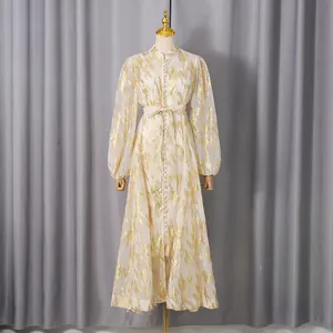 Close-up of elegant long dress with gold foil pattern, balloon sleeves and waist tie.