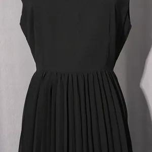 Nahaufnahme des eleganten schwarzen Plissee-Details an einem langen Kleid mit hoher Taille