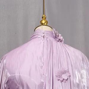 Detail view of lavender pleated high-neck dress featuring delicate fabric flower accents