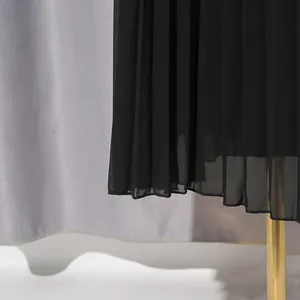Detailansicht des eleganten schwarzen plissierten Chiffonsaums eines langen Frühlingskleids.