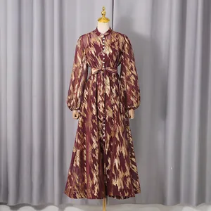 Elegant maroon long-sleeved dress with gold abstract pattern displayed on mannequin
