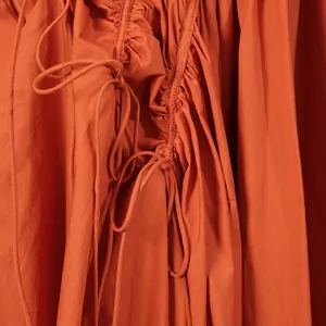 Dettaglio ravvicinato delle arricciature con coulisse su un abito lungo color terracotta