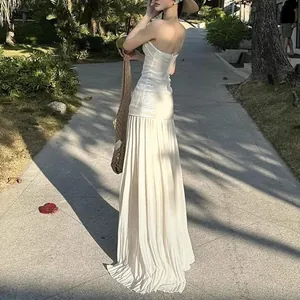 Detalle de un vestido largo plisado blanco palabra de honor en un entorno vacacional
