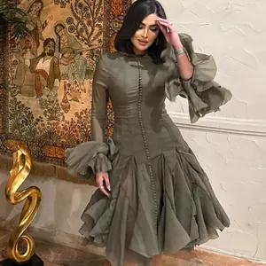 Detail view of ruffled cuffs and buttoned front on an elegant olive green gauze dress