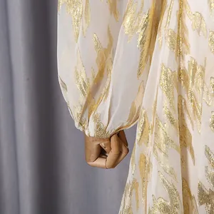 Macro detail of elegant dress featuring metallic gold leaf pattern on white sheer fabric lantern sleeve