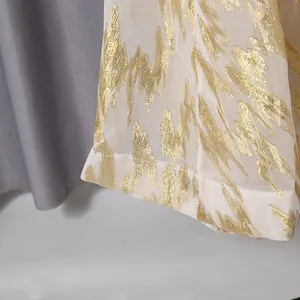 Close-up detail of high-quality white sheer fabric with elegant shimmering gold foil pattern