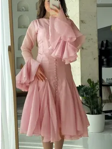 Elegant pink gauze dress with dramatic flared ruffle sleeves and button detail.