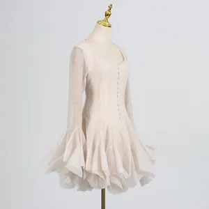 Detalle de vestido corto beige con puños con volantes y botones en la parte frontal.