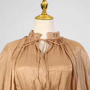Close-up of gold pleated dress detail with ruffled collar and elegant bow tie-up design