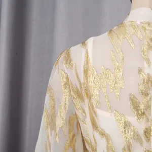 Close-up of elegant cream dress with intricate gold metallic abstract leaf patterns.