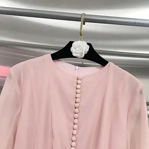 Close-up of elegant pink textured dress with button-front detail on a camellia hanger