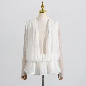 Detailansicht eines weißen Spitzen-Mesh-Kleides mit langen Ärmeln und Rüschensaum