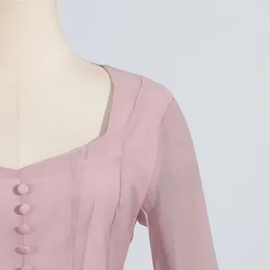 Vista detallada de un vestido rosa con escote cuadrado y botones forrados de tela