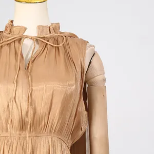 Close-up of shimmery pleated dress with ruffled tie neckline and metallic finish