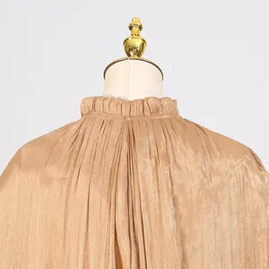 Detailed view of champagne gold pleated mock neck dress with satin-like texture