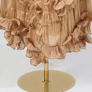 Detail view of champagne ruffled hemline on elegant pleated luxury midi dress