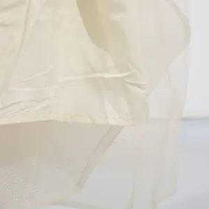 Detailopname van de stiksels en de dubbellaagse mesh-stof van een elegante crèmejurk