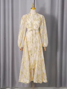 Elegant gold patterned maxi dress with long puff sleeves and a stylish waist bow tie