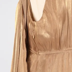 Close-up of invisible side zipper and metallic pleated fabric on a gold luxury dress