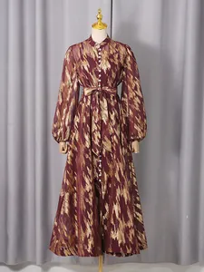 Elegant long-sleeved burgundy dress with metallic gold pattern and waist tie.