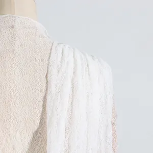 Detaillierte Nahaufnahme des filigranen weißen Blumen-Spitzenmusters am Kleid