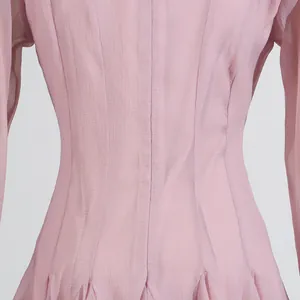 Detalle de la tela rosa claro con textura y pliegues ajustados en la cintura de un vestido