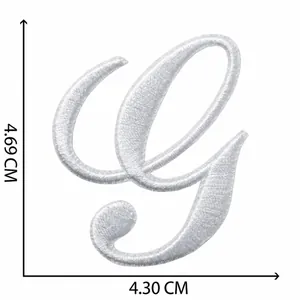 Gros plan d'un écusson brodé lettre G blanche avec dimensions 4,69 cm x 4,30 cm.