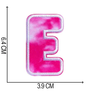 Detailed view of tie-dye embroidered letter E patch showing 6.4 cm by 3.9 cm dimensions