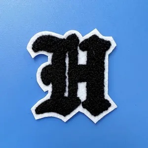 Gros plan montrant la texture de l'écusson brodé en chenille lettre H noir et blanc