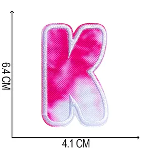 Close-up detail of tie-dye letter K embroidered patch showing dimensions 6.4 x 4.1 cm.