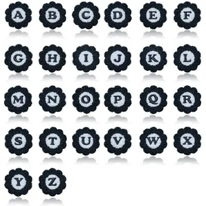 Macro detail of black and white flower-shaped chenille embroidered alphabet patches A-Z.