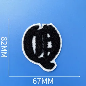 Gros plan d'un écusson brodé lettre Q en chenille noire avec taille 82x67mm