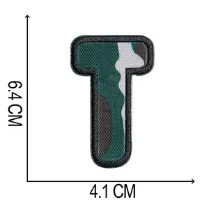 Dettaglio toppa ricamata lettera T mimetica con dimensioni 6,4 x 4,1 cm.