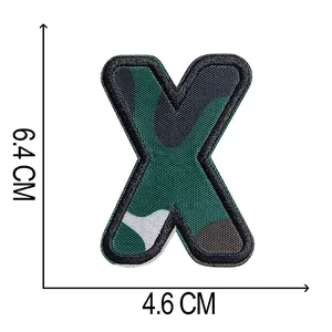 Dettaglio della toppa ricamata mimetica lettera X con dimensioni di 6,4 cm x 4,6 cm.