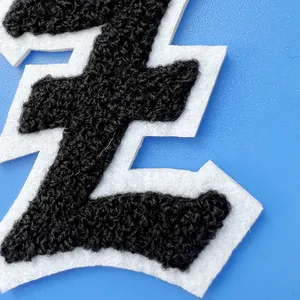 Gros plan d'un écusson en chenille noire avec bordure en feutre blanc pour vêtement