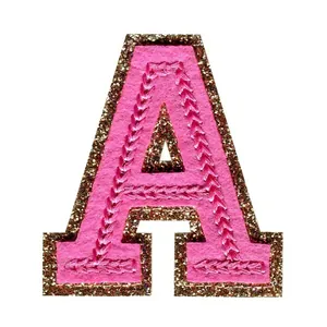 Nahaufnahme eines pinkfarbenen Buchstaben-A-Patches mit funkelndem goldener Glitzerrand