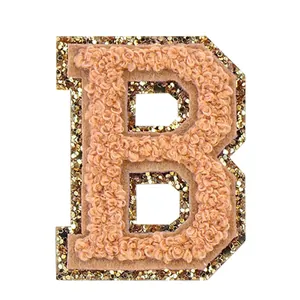 Dettaglio della toppa in ciniglia lettera B con bordo glitterato dorato per abiti.