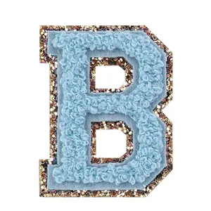 Dettaglio macro di una patch lettera B in ciniglia azzurra con bordo glitterato dorato