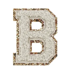 Dettaglio ravvicinato di una toppa in ciniglia bianca lettera B con bordo dorato glitterato