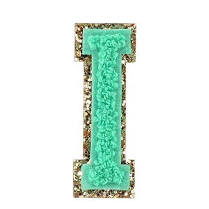 Dettaglio ravvicinato della toppa in ciniglia lettera I verde menta e bordo oro
