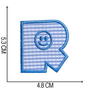 Detailansicht des blau karierten Buchstabe R Bügelbilders mit einem Smiley-Gesicht