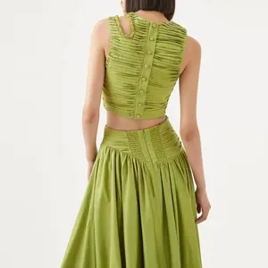 Vista detallada del conjunto plisado verde con espalda abotonada y falda larga.