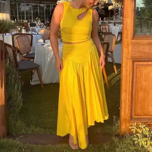 Detalle de conjunto amarillo de dos piezas con top corto con abertura y falda plisada.