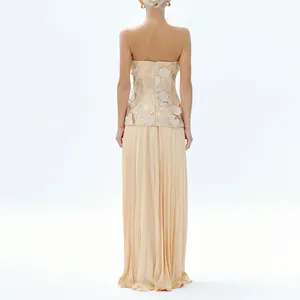 Detail view of an elegant strapless top with 3D floral patterns and a pleated maxi skirt.