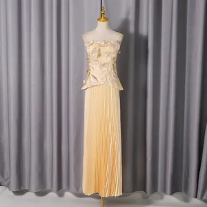 Detailed view of yellow two-piece set featuring 3D floral appliqués and pleated maxi skirt