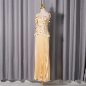 Elegant cream two-piece set with 3D floral strapless top and high-waisted pleated maxi skirt.