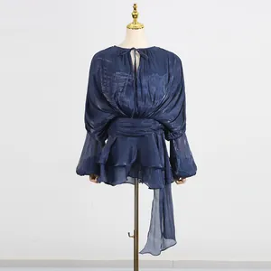 Detailed view of a shimmering blue mesh dress featuring pleated puff sleeves and ruffles