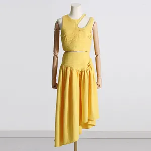 Conjunto amarillo de dos piezas con top recortado y falda plisada asimétrica en maniquí