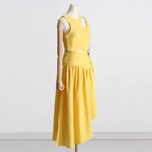 Vista lateral del conjunto amarillo de dos piezas con top corto asimétrico y falda midi.
